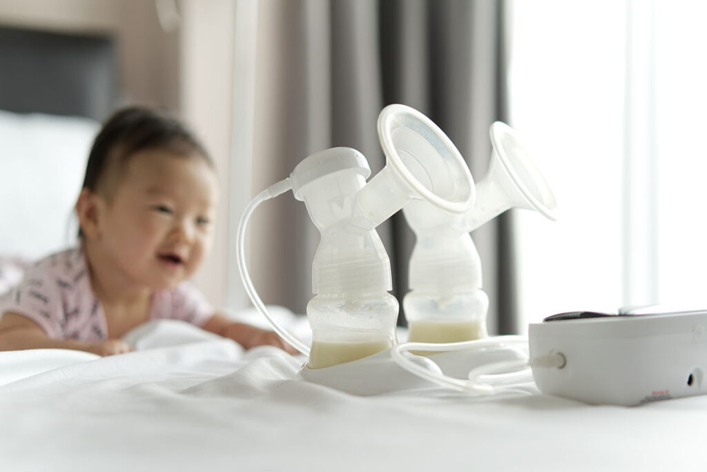 Breast milk in milk pump's bottles and pump machine on the bed w